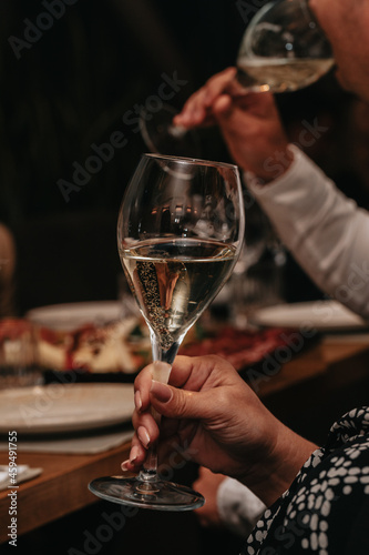 Elegant waiter pours champagne from bottle into glass at restaurant. Sommelier tasting white sparkling wine in restaurant. Copy space for text menu elegant or recipe on dark background.