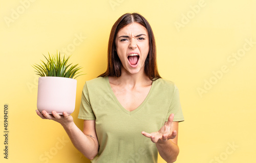 young hispanic woman looking angry, annoyed and frustrated. plant pot concept