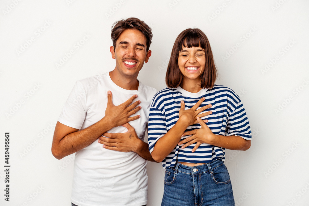 Fototapeta premium Young mixed race couple isolated on white background laughs happily and has fun keeping hands on stomach.