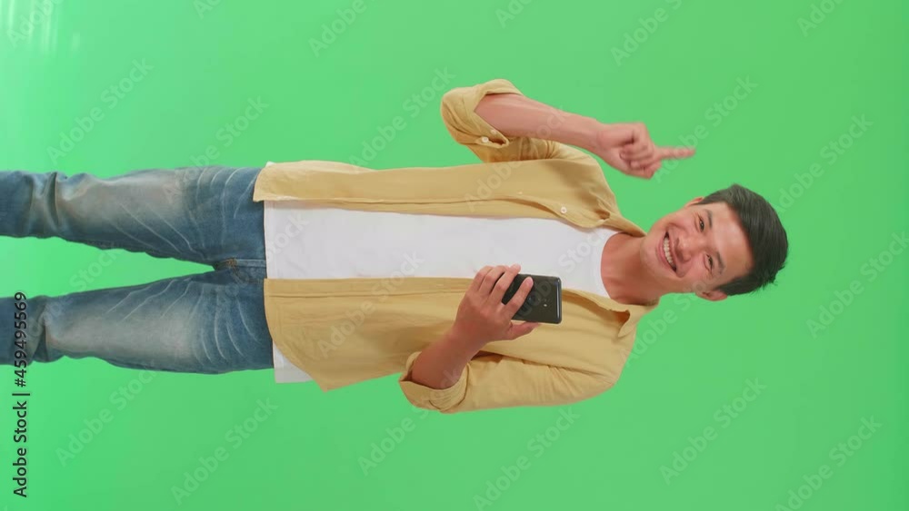 The Inspired Asian Man Flipping Through The Mobile Phone With A Smile Pointing Up While Standing In The Green Screen Studio
The Inspired Asian Man Flipping Through The Mobile Phone With A Smile Pointing Up While Standing In The Green Screen Studio