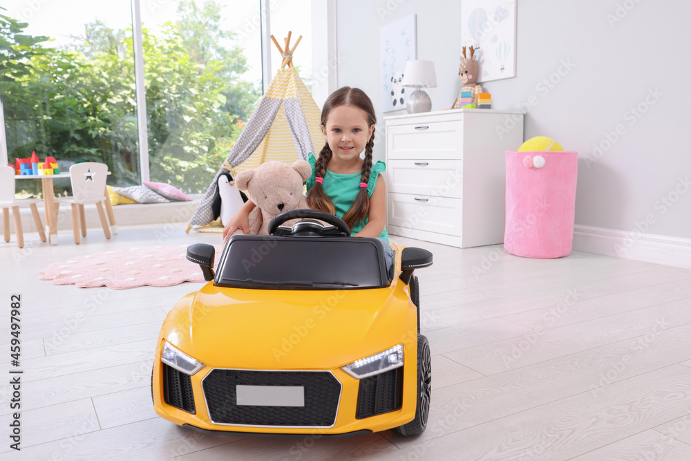 Adorable child with toy driving car in room at home Adorable child with toy driving car in room at home