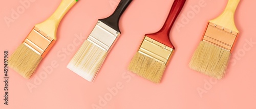 Four paint brushes lined up on a pink background.