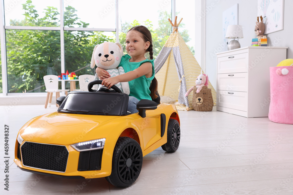 Adorable child with toy driving car in room at home Adorable child with toy driving car in room at home