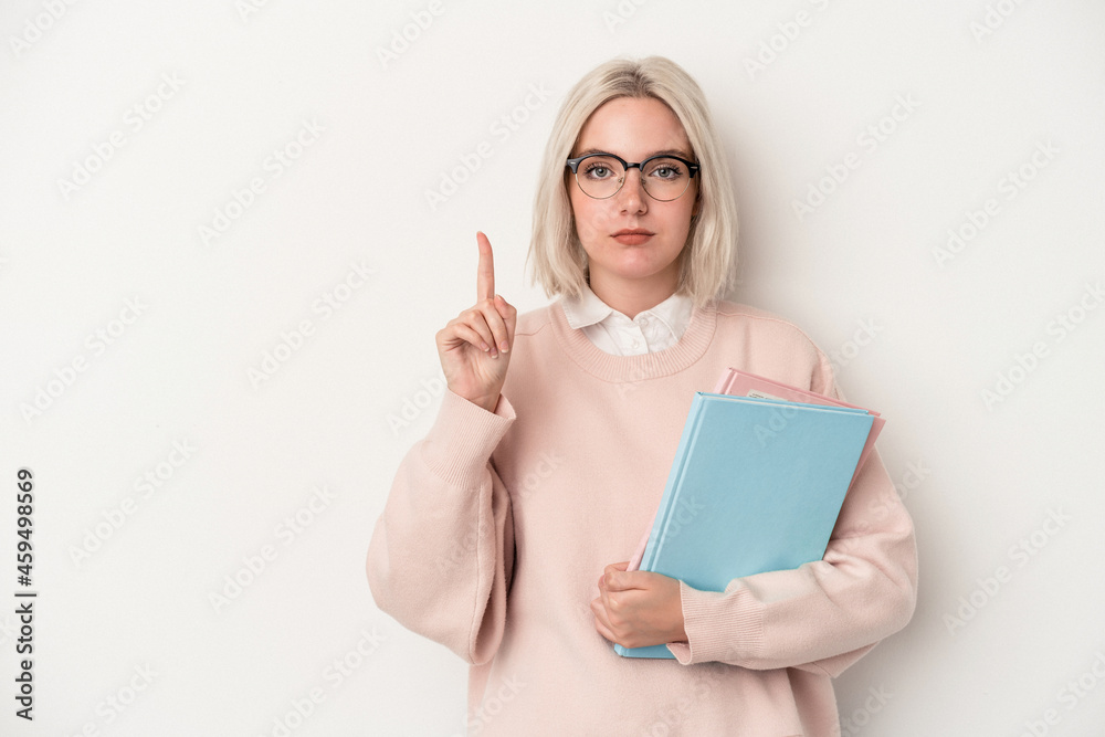 Young caucasian student woman holding books isolated on white background showing number one with finger. Young caucasian student woman holding books isolated on white background showing number one with finger.