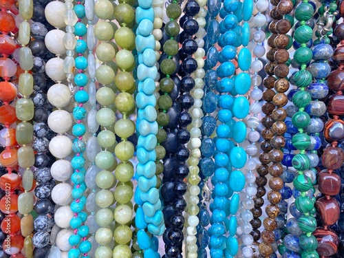 Colorful beads background. Beads made natural gems  turquoise, malachite, mother pearl, jade, quartz, agate, lapis lazuli, jasper, cacholong, tiger's eye stone, topaz, fluorite. Beautiful bijouterie. photo