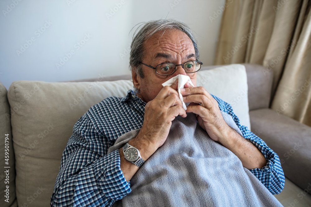 Sick senior man in bed at home. Ill Caucasian elderly man with seasonal infections, flu, allergy sitting in bed, covered with a blanket with high fever and flu. Healthcare and medicine concept. Sick senior man in bed at home. Ill Caucasian elderly man with seasonal infections, flu, allergy sitting in bed, covered with a blanket with high fever and flu. Healthcare and medicine concept.