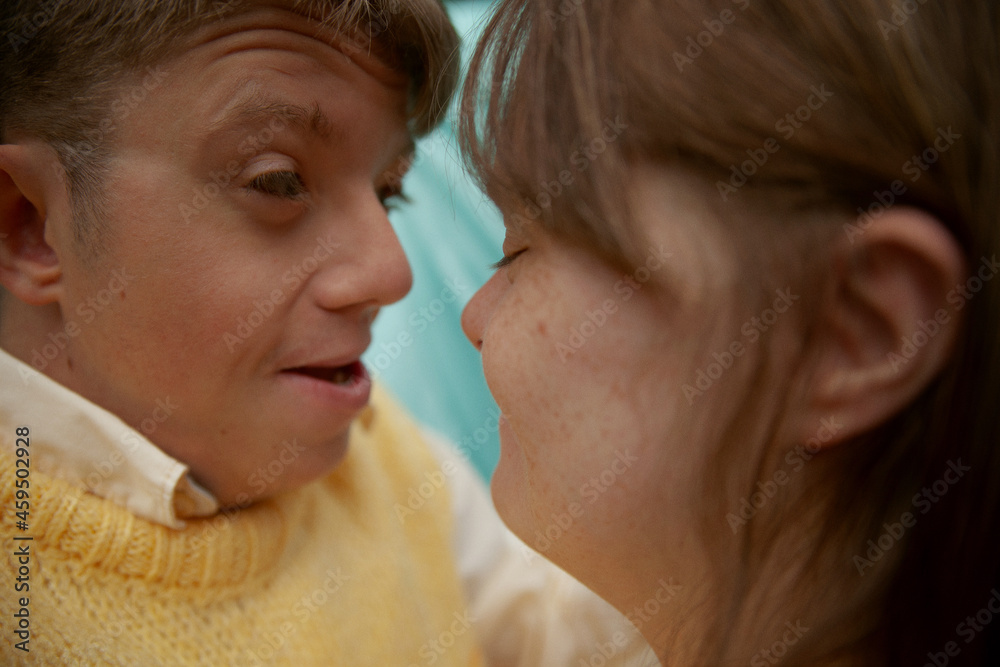 Face to face portrait of young couple with Down Syndrome and Foetal Alcohol Syndrome smiling in front of blue background Face to face portrait of young couple with Down Syndrome and Foetal Alcohol Syndrome smiling in front of blue background