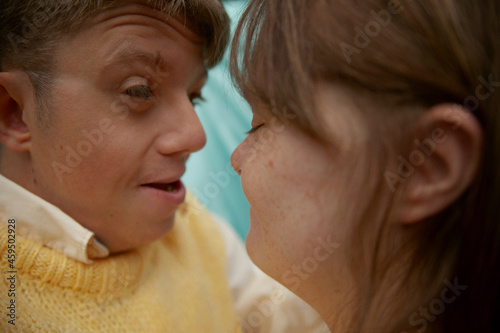 Face to face portrait of young couple with Down Syndrome and Foetal Alcohol Syndrome smiling in front of blue background