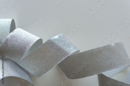 roll of silver crepe paper ribbon partly unrolled on a gray background 
