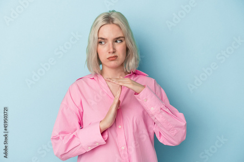 Young caucasian woman isolated on blue background showing a timeout gesture. © Asier