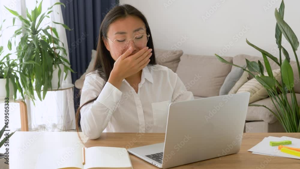 Exhausted asian attractive business woman yawn working with her notebook sitting at her desk Exhausted asian attractive business woman yawn working with her notebook sitting at her desk