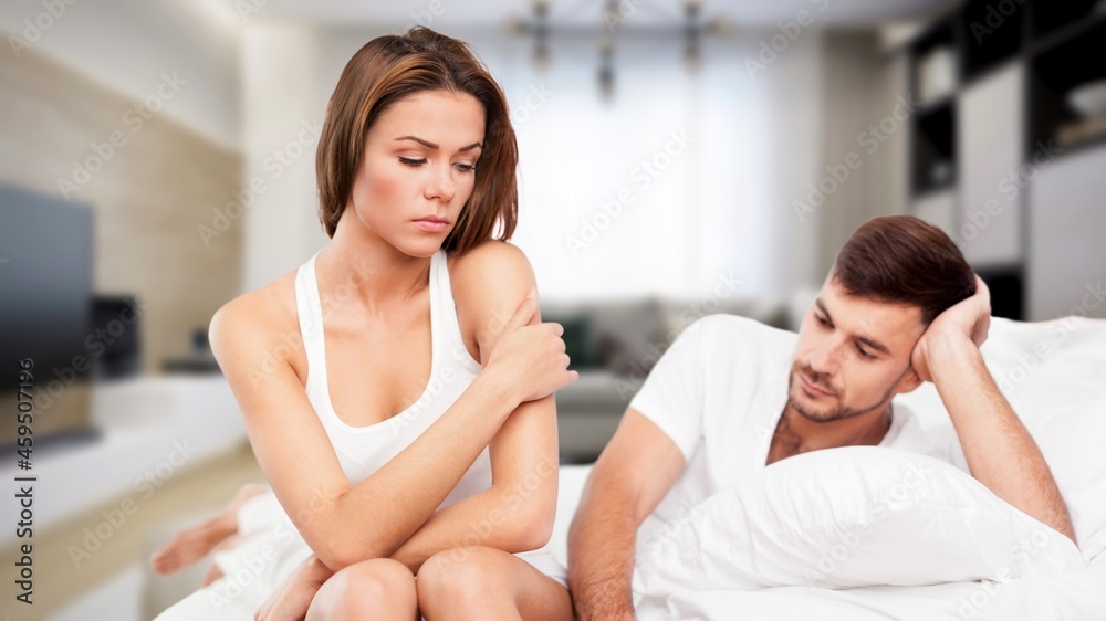 Depressed young man sitting in bed cannot sleep from insomnia