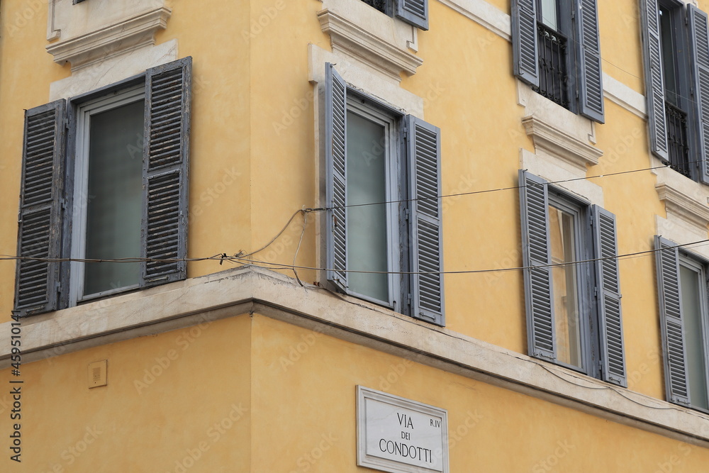 Yellow Ochre Building Facade Detail with Windows and Open Shutters in Rome, Italy