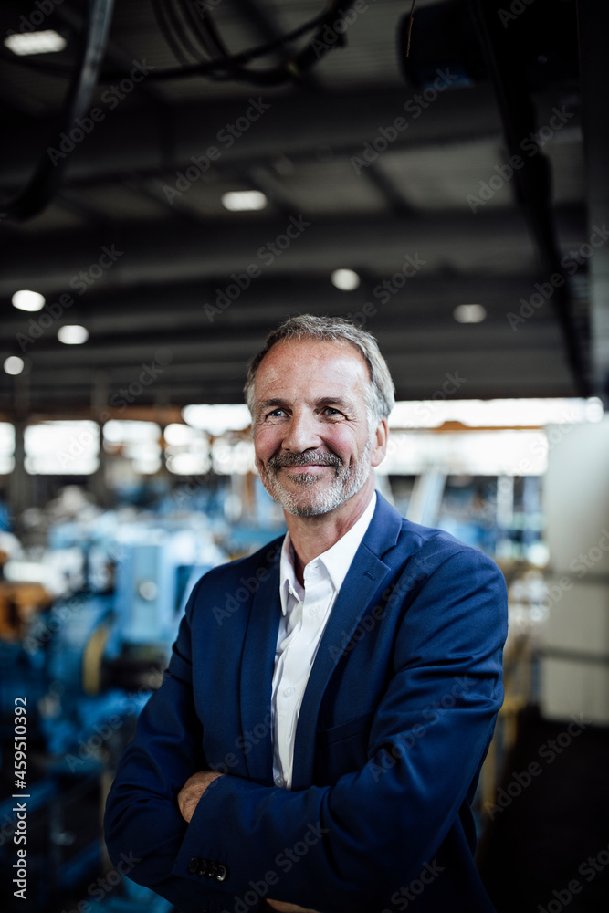 Smiling senior businessman with arms crossed at metal industry Smiling senior businessman with arms crossed at metal industry