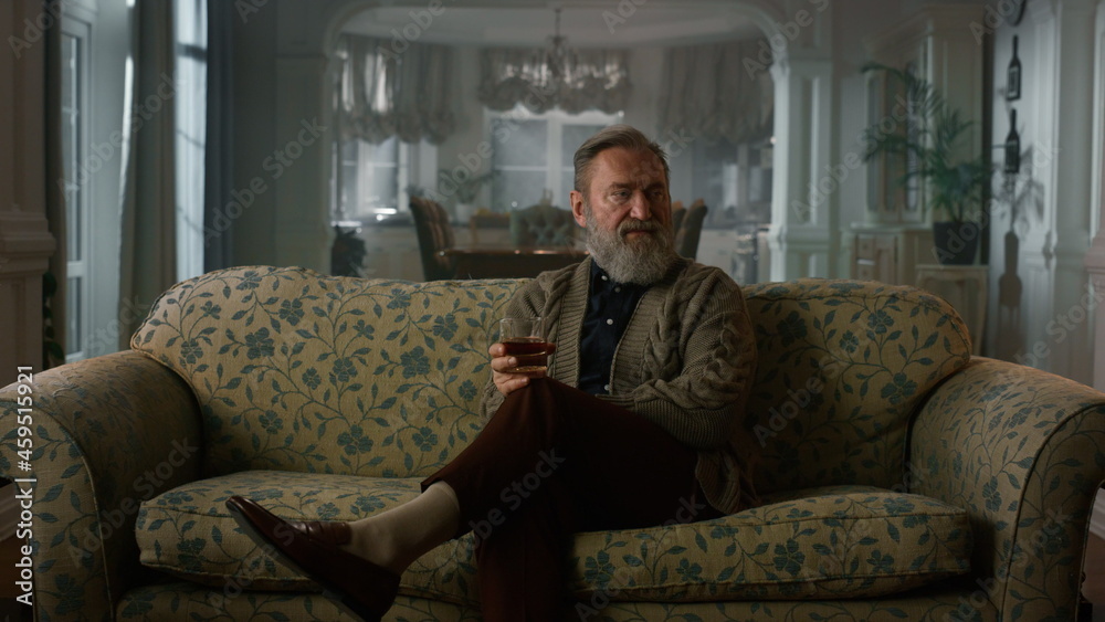 Fototapeta premium Thoughtful mature man thinking with alcohol glass. Rich old grandfather relaxing
