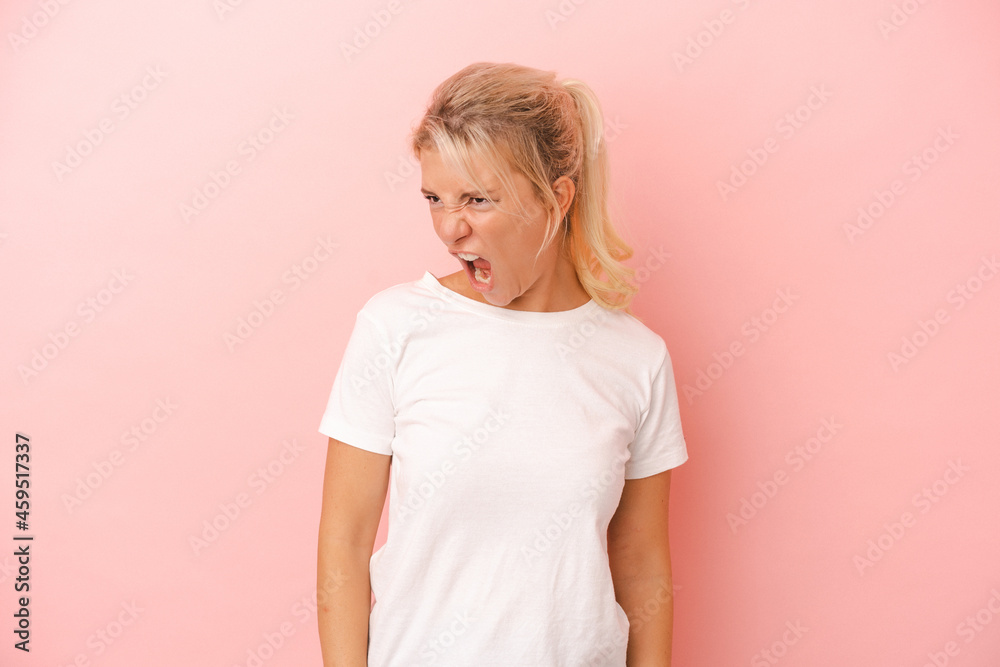 Young Russian woman isolated on pink background shouting very angry, rage concept, frustrated.
