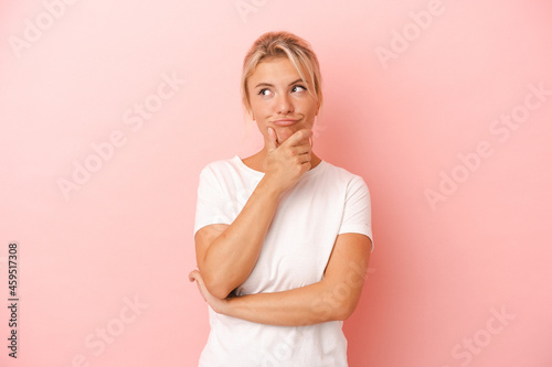 Young Russian woman isolated on pink background relaxed thinking about something looking at a copy space.