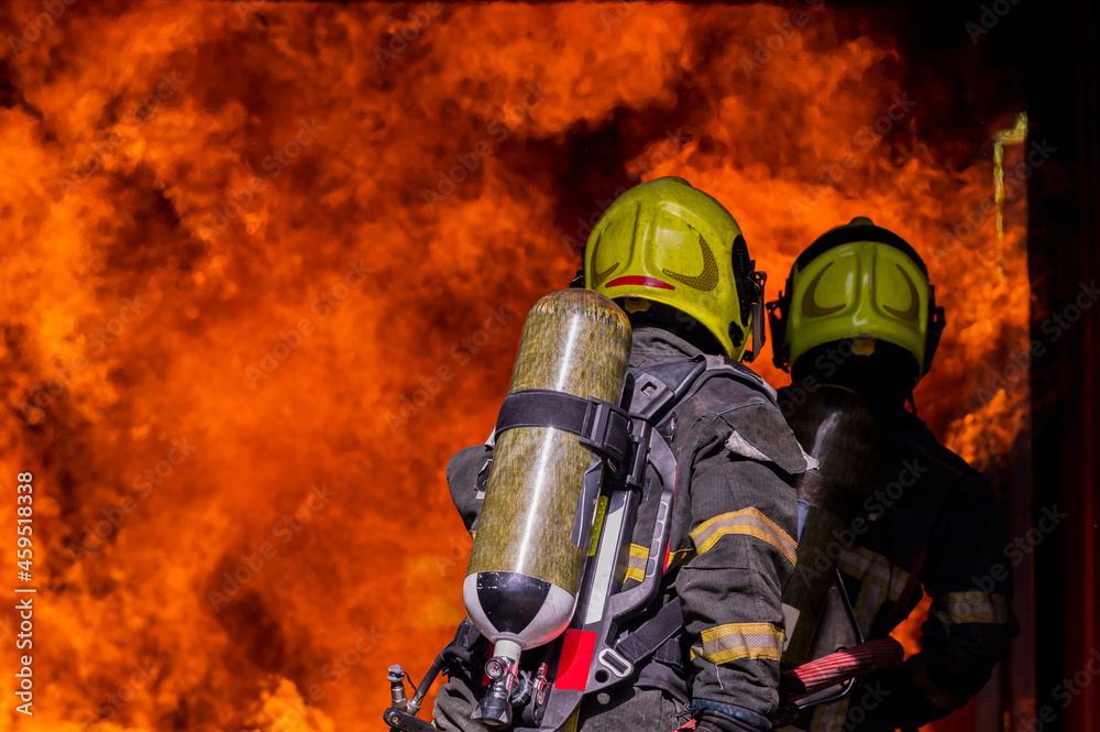 Fototapeta premium firefighters wearing fire fighter suit for safety and using twirl water extinguisher for fighting the fire flame in emergency situation.. - Safety Firefighter and industrial concept.