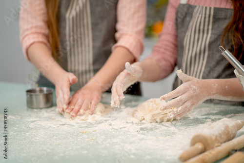 Close up hand of two woman thresh flour for cooking with other tools or accessories in the kitchen look like family activities together during holiday or relax time.