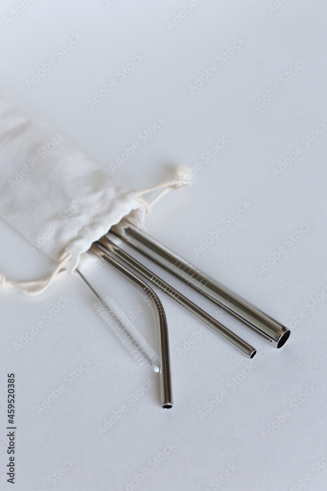 Stainless three steel straws in white bag on gray background. Stainless three steel straws in white bag on gray background.