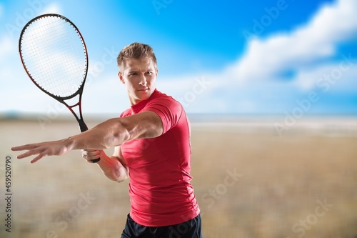 Young man playing beach tennis on sand background. Professional sport concept © BillionPhotos.com