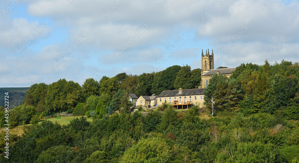 Fototapeta premium Village of Tintwistle on a Derbyshire hillside church houses and trees.