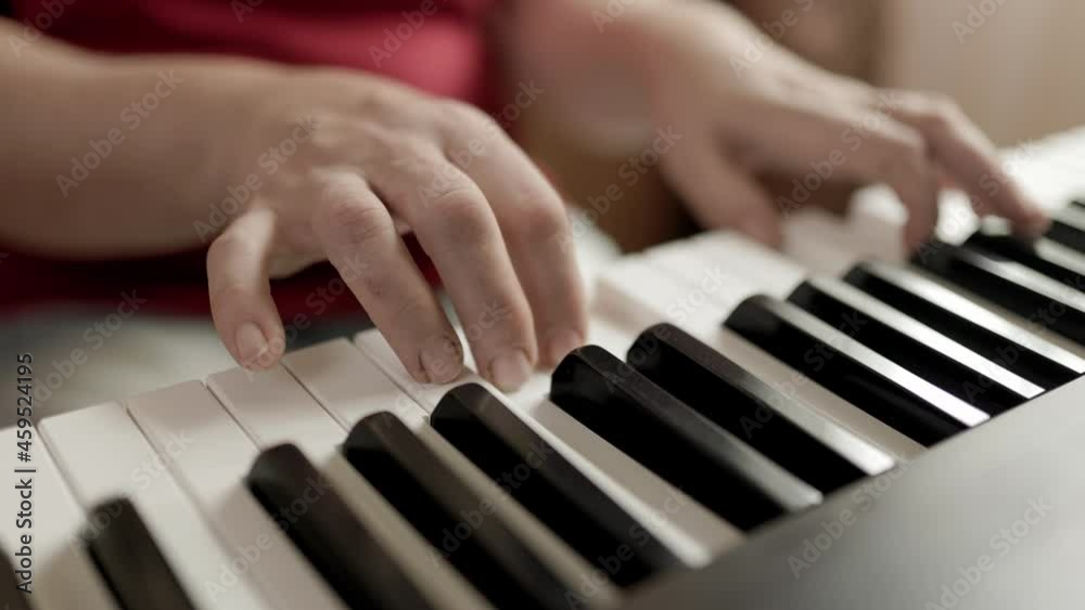 Close up of woman's hand playing the electric piano. Female synthesizer player. Woman practicing lessons at home on her black electric piano. Close up of woman's hand playing the electric piano. Female synthesizer player. Woman practicing lessons at home on her black electric piano.