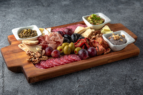 Plateau snack for wine. Prosciutto, smoked sausage, olives, cheese, pates. Food for a large company. Ready menu for the restaurant. Neutral gray blue textured background