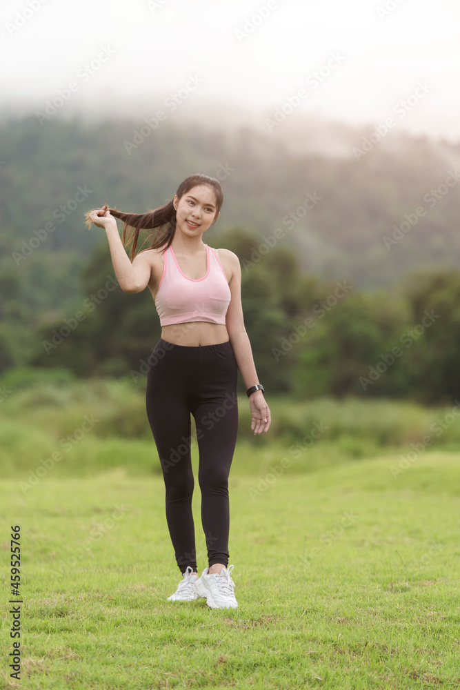 A sporty woman in sportswear exercises at the garden in front of her home A sporty woman in sportswear exercises at the garden in front of her home