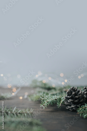 Minimalistic winter christmas background. Fir branches and cones on a wooden table.