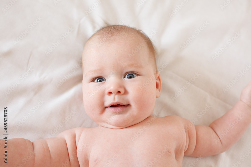 small child, baby lies on his stomach and smiles. On a white background. Newborn baby. three months old baby. A baby of European appearance. selective focus small child, baby lies on his stomach and smiles. On a white background. Newborn baby. three months old baby. A baby of European appearance. selective focus