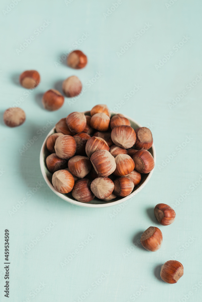 Pile of hazelnuts filbert in a bowl on a light blue background Pile of hazelnuts filbert in a bowl on a light blue background