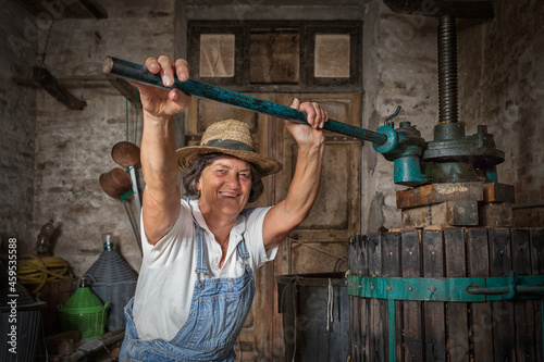 Ταπετσαρία Grape harvest: Old woman smiling winemaker  working on a traditional winepress for the must pressing