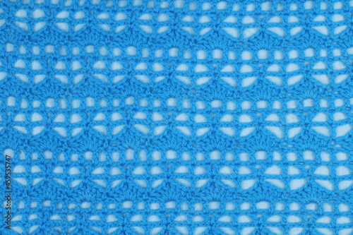 A blue crochet sample on a white fabric background. 
