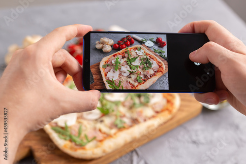 Smartphone shot food. Italian traditional pizza with cheese, ham and mushrooms. Social networks and delivery food application concept.