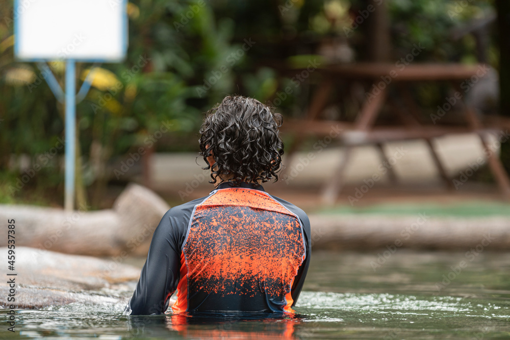Joven adolescente disfrutando dentro de una piscina térmica natural  del volcán Arenal - obrazy, fototapety, plakaty 