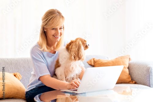 Middle aged businesswoman sitting on the sofa and using her laptop