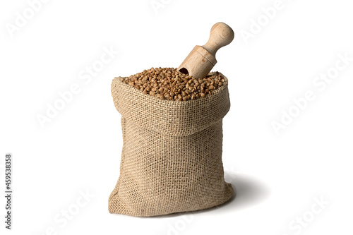 Buckwheat in a burlap sack and a wooden scoop. Close-up. On white background.