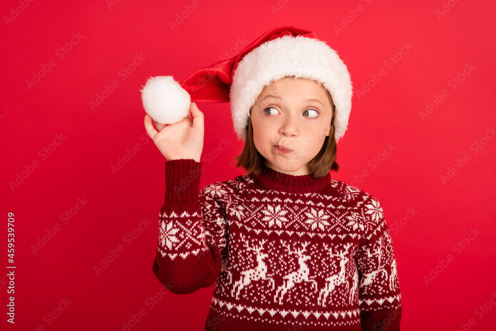 Photo of little girl curious interested hold fluffy ball wear santa hat eve time winter isolated over red color background Photo of little girl curious interested hold fluffy ball wear santa hat eve time winter isolated over red color background