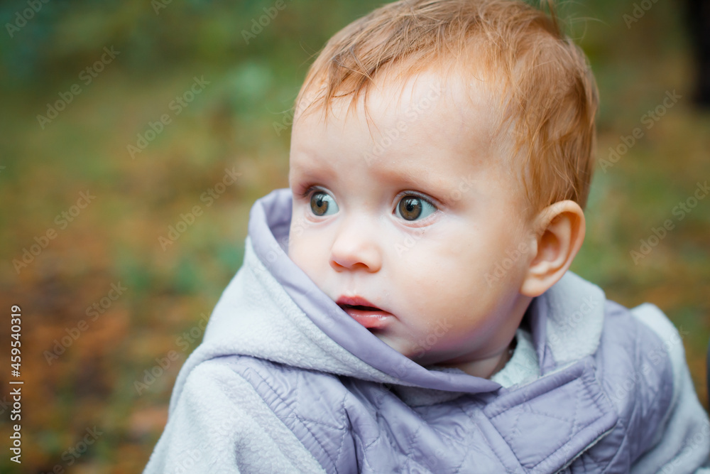 Scared baby looks aside. A small child looks puzzled. A girl in a purple jumpsuit in nature. Scared baby looks aside. A small child looks puzzled. A girl in a purple jumpsuit in nature.