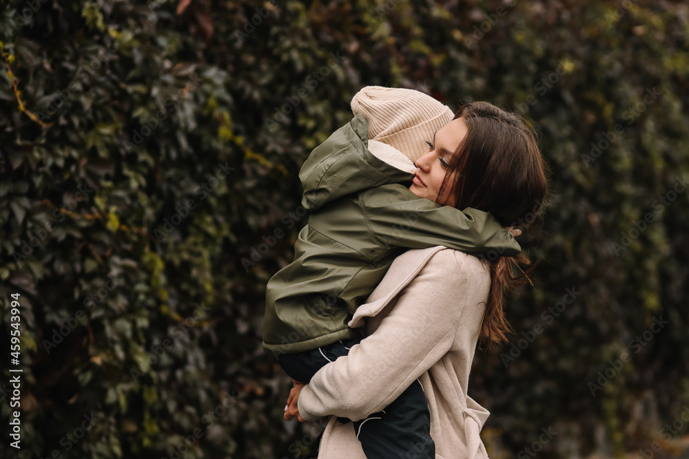 Happy cheerful mother and a small child son in warm clothes walking among plants in an autumn park in nature in fall outdoor, selective focus Happy cheerful mother and a small child son in warm clothes walking among plants in an autumn park in nature in fall outdoor, selective focus