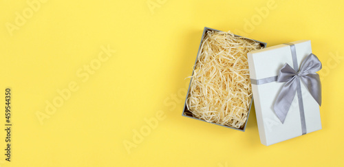 Gift box with filler on a yellow background for product advertising. Open gift box mockup, flat lay