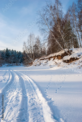 Winter landscape at sunset. The riverbed, spruce and birch trees are a truly Russian landscape.