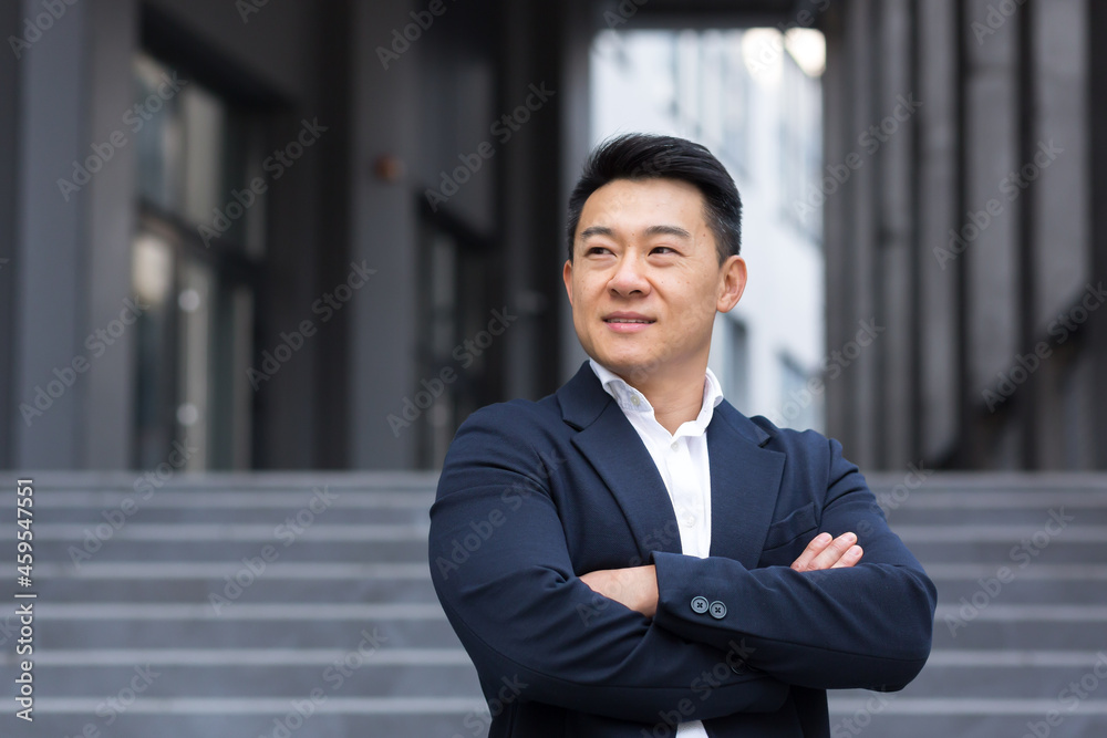 Portrait of Asian cheerful and successful businessman near office in business suit confident manager salesman broker smiling Portrait of Asian cheerful and successful businessman near office in business suit confident manager salesman broker smiling
