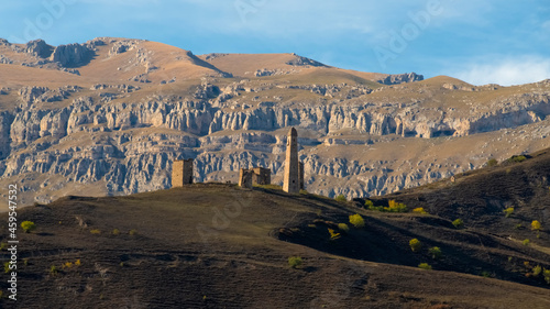 Erzi towers complex in Ingushetia, Russia. Old stone tower complex. Impressive rocky wall of the Caucasus mountains is on the background. Aerial view  photo