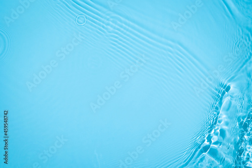 Transparent blue colored clear water surface texture with ripples, splashes and bubbles. Abstract nature background Water waves in sunlight with copy space Cosmetic moisturizer micellar toner emulsion © Aleksandra Konoplya