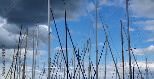 Masts of small sailboats moored in the harbor on the lake.