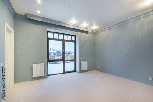 A large room in blue tones, unfurnished, with a panoramic window with a beautiful view. Interior of a cottage or townhouse