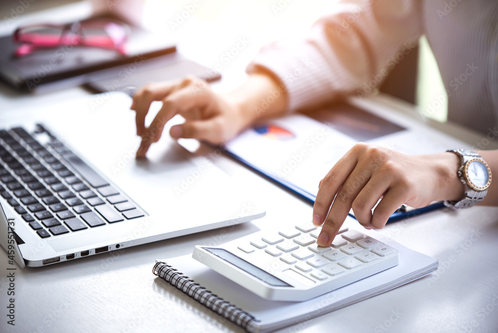 business woman or accountant who are using a calculator to calculate business data Accounting documents and laptop computer at the office business idea business woman or accountant who are using a calculator to calculate business data Accounting documents and laptop computer at the office business idea