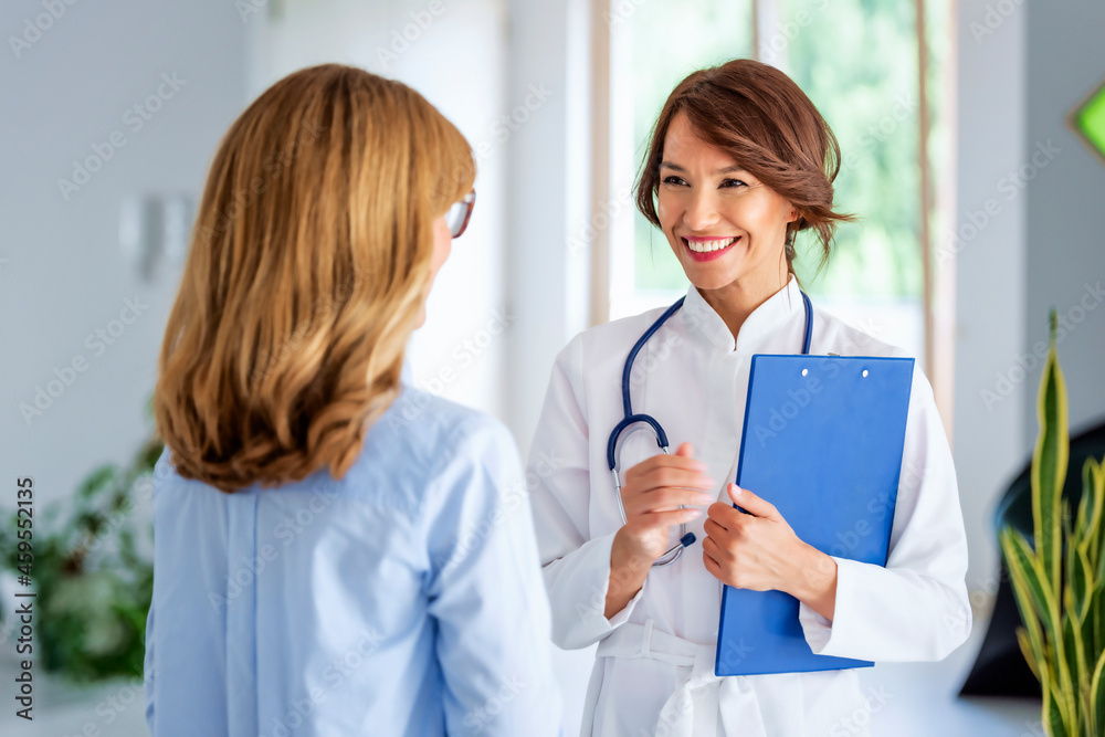 Female doctor consulting her patient while standing in doctor's office Female doctor consulting her patient while standing in doctor's office